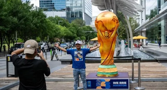 FILE PHOTO: A man poses for a picture next to a replica of the World Cup trophy in downtown Houston, Texas, on June 10, 2026, ahead of the 2026 FIFA World Cup. (Photo by RONALDO SCHEMIDT / AFP)